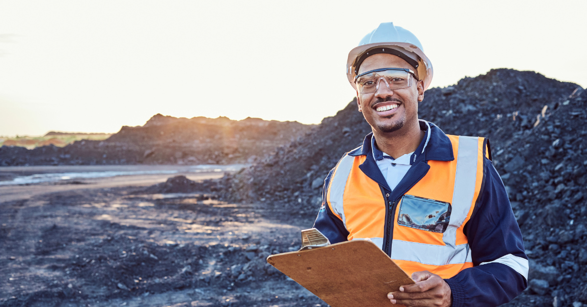 Smiling worker holding a clipboard at a surface coal mine after completing Standard 11 Surface Induction training.