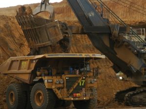 Excavator loading dirt into a mining truck at a coal mine site.